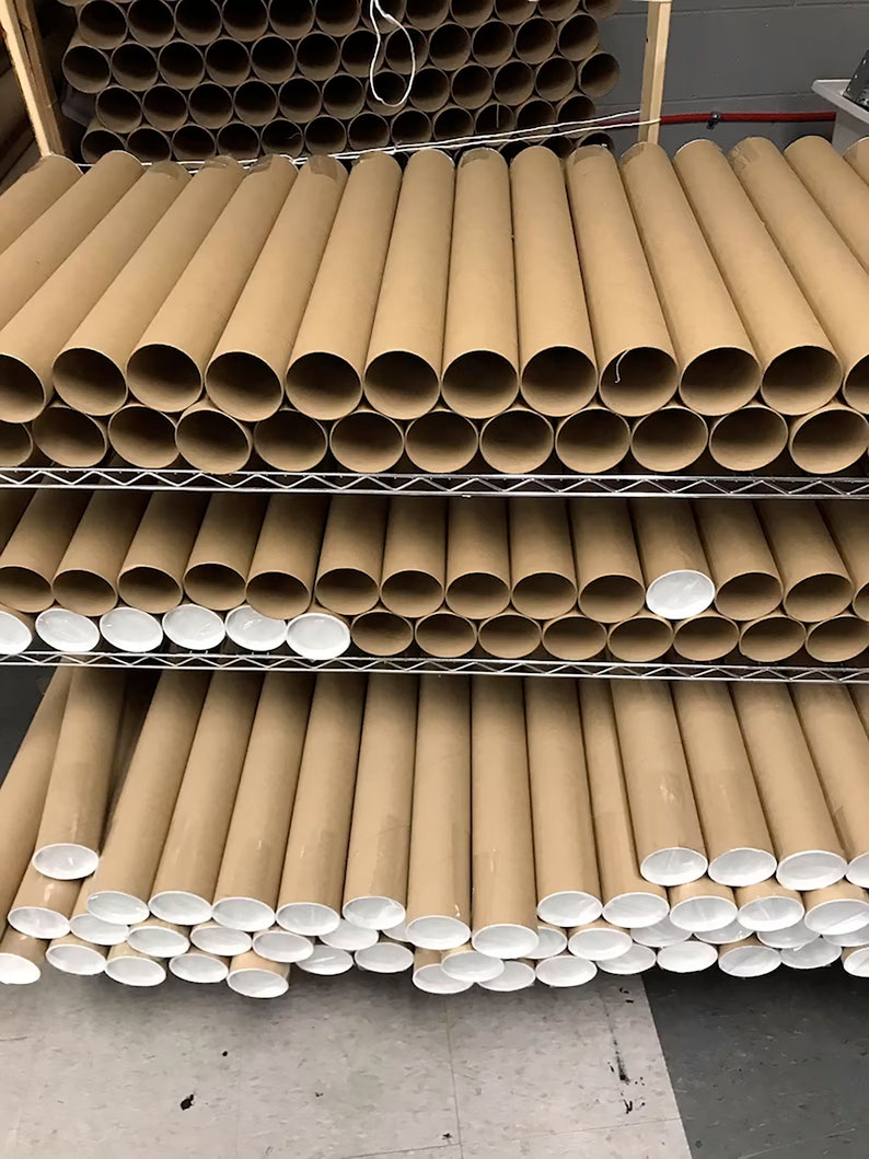 May include: A stack of brown cardboard mailing tubes with white end caps. The tubes are stacked on a metal shelf.