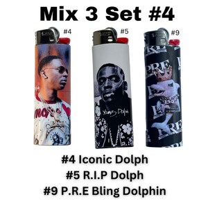 以下が含まれることがあります： ユニークなデザインのライター3個セット。1つは「#4 Iconic Dolph」の文字が入った肖像画、もう1つは「#5 R.I.P Dolph」の文字が入った白黒の肖像画、3つ目は「#9 P.R.E Bling Dolphin」の文字が入ったイルカのグラフィックです。