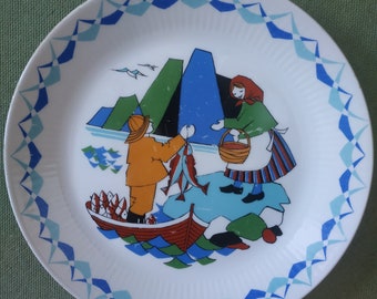 May include: A white ceramic plate with a blue and white border. The center of the plate features a colorful illustration of two people fishing in a boat with a mountain range in the background.