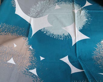 Puede incluir: Tela doblada con un patrón repetitivo de círculos turquesa, grises y blancos. El diseño incluye acentos triangulares blancos y detalles texturizados, creando una estética moderna.