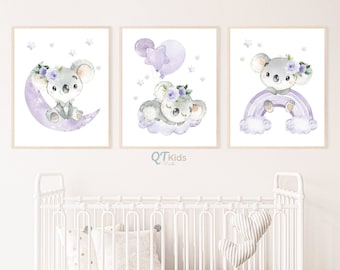 Op de afbeelding: Drie aquarelprints met een koalabeer met paarse bloemen in zijn haar. De eerste print toont de koala die op een paarse halve maan zit. De tweede print toont de koala die een paarse ballon met een ster vasthoudt. De derde print toont de koala die op een paarse regenboog zit.