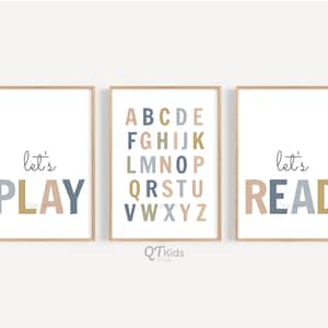 May include: Three framed prints with a white background and a light wood frame. The left print says "let's PLAY" in blue, gold, and pink letters. The middle print has the alphabet in different colors. The right print says "let's READ" in blue, gold, and pink letters.