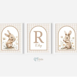 May include: Three white framed prints with a gingham background. Each print features a brown bunny with a flower in its paw, a brown letter R, and the name Riley.