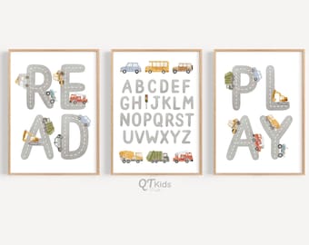 Puede incluir: Tres impresiones de arte de pared imprimibles que presentan las palabras "READ", "PLAY" y el alfabeto en una fuente gris y blanca. Cada letra está delineada con un camino gris y decorada con vehículos de juguete coloridos.