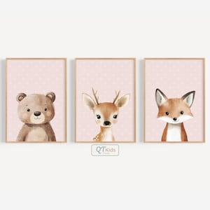 Puede incluir: Tres láminas enmarcadas para la guardería con un oso, un ciervo y un zorro. Cada animal está representado en un estilo suave de acuarela sobre un fondo rosa con lunares. Los marcos son de color madera clara.