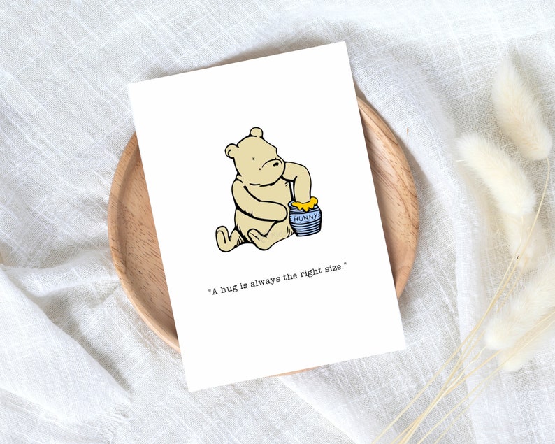 Puede incluir: Una ilustraci&oacute;n de dibujos animados de un oso blanco sosteniendo un tarro de miel azul y amarillo. El texto "A hug is always the right size." est&aacute; debajo de la ilustraci&oacute;n.