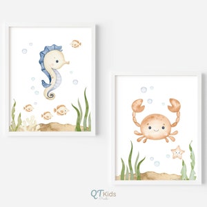 May include: Two watercolor illustrations of sea creatures in white frames. The first illustration features a blue and white seahorse with a light brown background and small orange fish. The second illustration features a brown crab with a light brown background and a yellow starfish.