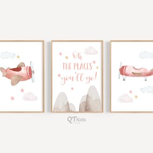 May include: Three watercolor prints featuring a pink airplane flying in a blue sky with white clouds and gold stars. The middle print has the text "Oh the places you'll go!" in pink lettering.