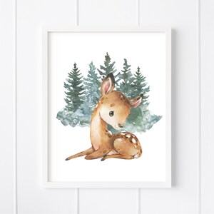 K&ouml;nnte beinhalten: Eine Aquarell-Illustration eines Rehs, das in einem Wald aus gr&uuml;nen B&auml;umen sitzt. Das Reh ist braun mit wei&szlig;en Flecken und hat gro&szlig;e, braune Augen. Die B&auml;ume sind in Gr&uuml;n- und Blaut&ouml;nen gemalt.