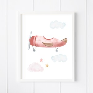 May include: A watercolor illustration of a pink airplane flying in the sky with clouds and stars. The airplane has a brown propeller and a brown tail.