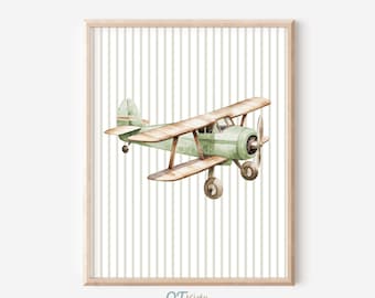 May include: A framed watercolor print of a vintage biplane in shades of green and brown. The biplane is set against a backdrop of vertical, light green and white stripes. The print is in a light wood frame. The text "QTKids" is in the bottom left corner.