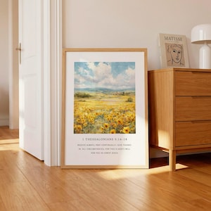 May include: A framed wall art print featuring a landscape painting of a vibrant yellow sunflower field under a blue sky with white clouds. Below the image, the text reads 1 THESSALONIANS 5:16-18 and REJOICE ALWAYS, PRAY CONTINUALLY, GIVE THANKS IN ALL CIRCUMSTANCES; FOR THIS IS GOD'S WILL FOR YOU IN CHRIST JESUS.