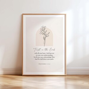 May include: Framed art print featuring the text "Trust in the Lord" with a floral line drawing. The artwork includes the scripture Proverbs 3:5-6. The print has a neutral color palette with a beige background and a light brown frame.