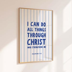 Puede incluir: Una impresión enmarcada con un borde dorado presenta el texto "I CAN DO ALL THINGS THROUGH CHRIST WHO STRENGTHENS ME" en azul. El fondo tiene rayas verticales en azul claro y blanco. El texto "Filipenses 4:13" está en la parte inferior.