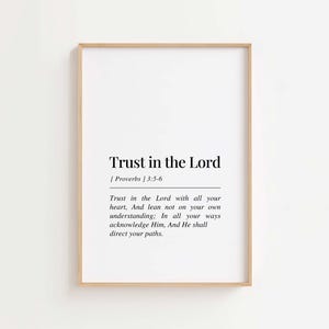 Peut inclure: Une affiche encadrée avec le texte "Trust in the Lord" et une citation de Proverbes 3:5-6. L'affiche a un fond blanc avec du texte noir et un cadre en bois brun clair. La citation encourage la foi et l'orientation.
