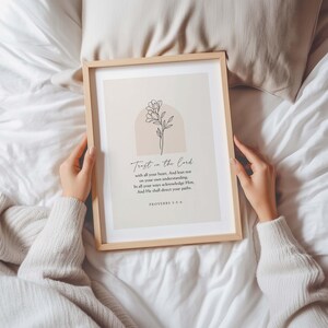 May include: A framed print with the text "Trust in the Lord" and a floral illustration. The print is in a light wooden frame and is displayed on a white surface. The text includes the Bible verse Proverbs 3:5-6.