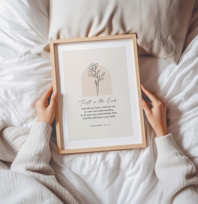 May include: A framed print with the text "Trust in the Lord" and a floral illustration. The print is in a light wooden frame and is displayed on a white surface. The text includes the Bible verse Proverbs 3:5-6.