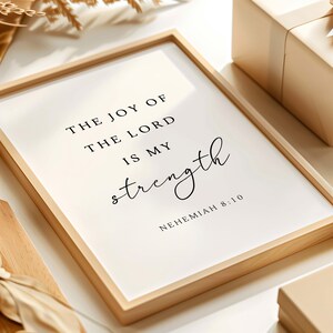 May include: A framed print with a white background and black text that reads "The joy of the Lord is my strength, Nehemiah 8:10".