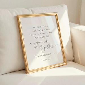 May include: A framed print with a gold-colored frame. The print features elegant script and text that reads, "SO THEY ARE NO LONGER TWO, BUT ONE FLESH. THEREFORE WHAT GOD HAS joined together. LET NO ONE SEPARATE. Matthew 19:6."