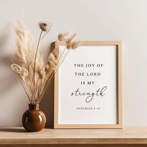 May include: A framed print with a white background and black text that reads "The joy of the Lord is my strength" with the scripture reference "Nehemiah 8:10" below.