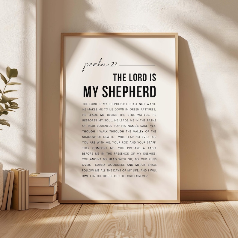 May include: A framed print with the text "Psalm 23: The Lord is My Shepherd" in a minimalist design. The text is in black on a white background, with a wooden frame. The print is displayed in a well-lit room.