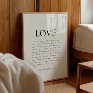May include: A beige poster with a black frame and the word "LOVE" in large black letters. The poster features a quote about love from 1 Corinthians 13:4-8.