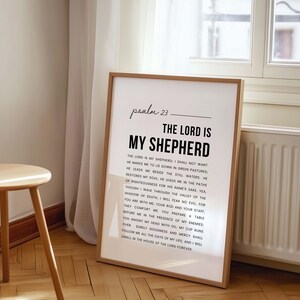 May include: A framed print with the text "psalm 23" and "The Lord is My Shepherd" in a modern font. The full text of Psalm 23 is printed below in a simple, readable font. The frame is a light brown color.