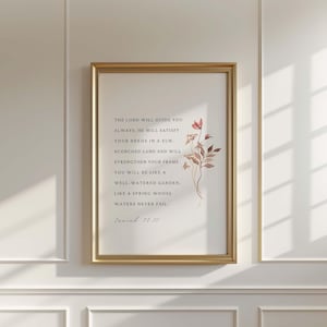 Puede incluir: Una impresión enmarcada con un marco dorado y un fondo blanco. La impresión presenta una ilustración de acuarela de un arreglo floral con flores rosas y marrones. El texto dice: "El Señor te guiará siempre: Él satisfará tus necesidades en una tierra abrasada por el sol y fortalecerá tu marco. Serás como un jardín bien regado, como un manantial cuyas aguas nunca se agotan. Isaías 58:11"