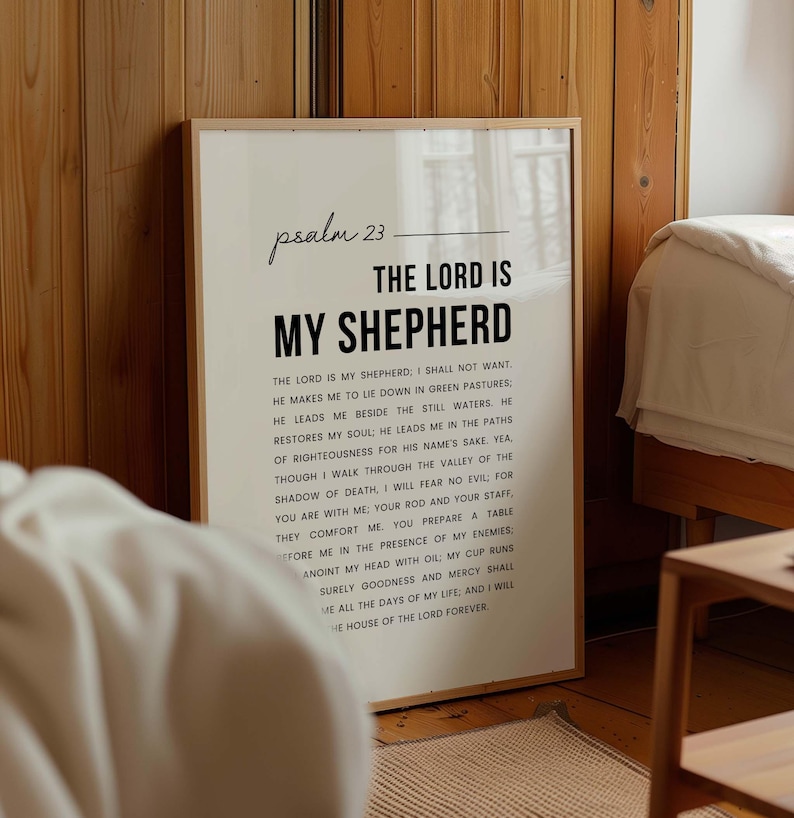 May include: A framed print with the text "Psalm 23: The Lord is My Shepherd" in a minimalist style. The text is in black on a white background, with the full verse printed below. The frame is a light wood color.