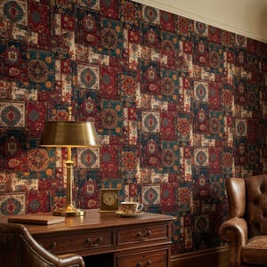 May include: A room with a patterned wallpaper in shades of red, blue, and cream. A wooden desk with a brass lamp, books, and a teacup sits in front of the wallpaper. A leather armchair with a plaid blanket is in the corner.