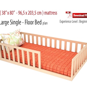 May include: DIY plan for a large single floor bed, designed for a 38" x 80" mattress. The bed frame is made of light wood and has a simple, modern design. The bed is shown with a red and white patterned mattress and a floral pillow.