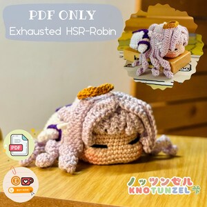 以下が含まれることがあります： 紫色の髪とハローを持つキャラクターの、かぎ針編みで作られたぬいぐるみ。おもちゃは横向きに寝ていて、目は閉じられています。おもちゃには「PDF ONLY Exhausted HSR-Robin」と「Knotunzel」のラベルが付いています。