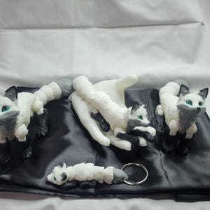 May include: Four white and gray fox figurines with black eyes. The foxes are posed in different positions, including sitting, lying down, and standing. The figurines are made of a smooth, white material and have a realistic appearance.