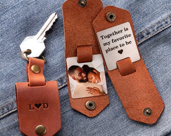 May include: A brown leather keychain with a photo insert and a metal tag that says "Together is my favourite place to be" with a heart symbol. The keychain also has a small leather tag with the letters "L♥D".