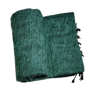 Op de afbeelding: Een opgerolde, getextureerde, groene deken met een franje van zwarte kwastjes. De deken is gemaakt van een geweven materiaal en de kleur is een diepe, rijke tint groen. De deken is over zichzelf gevouwen.