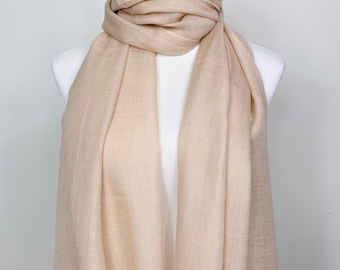 May include: A beige scarf draped over a white mannequin. The scarf is made of a soft, woven material and is wrapped around the mannequin's neck. The scarf hangs down in soft folds, showcasing its texture and color. The neutral tone makes it a versatile accessory.