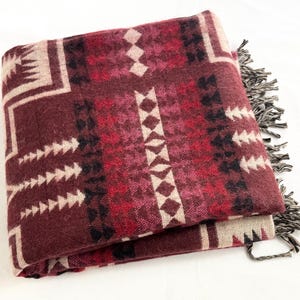 May include: A brown, red, and cream patterned throw blanket with fringe on the edges.
