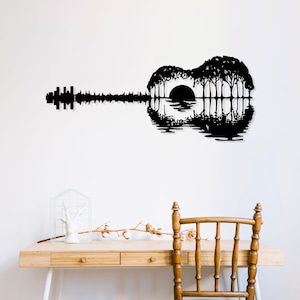 Puede incluir: Silueta negra de una guitarra acústica con una puesta de sol y árboles reflejados en el cuerpo de la guitarra.