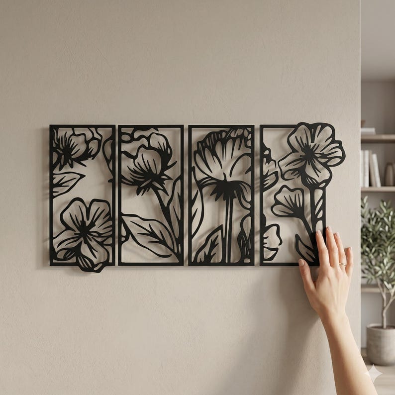 May include: Black metal floral wall art composed of four rectangular panels. Each panel features a different flower design with leaves and stems. The art is mounted on a light beige wall, creating a contrast with the dark metal.