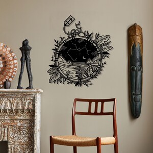 Puede incluir: Arte de pared en blanco y negro con una ilustraci&oacute;n estilizada de un reloj de bolsillo con una constelaci&oacute;n en su interior. El reloj est&aacute; rodeado de follaje y tiene una peque&ntilde;a flecha en la parte superior.