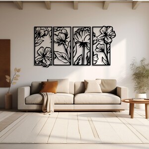 May include: Four-panel black metal floral wall art. Each panel features a different flower design with stems and leaves. The artwork is displayed above a beige sofa with decorative pillows and a throw blanket. A round wooden side table and a plant are also in the room.