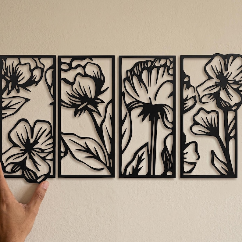 May include: Four black metal floral wall art panels. Each panel features a different flower design with intricate cut-out details. The panels are rectangular and arranged side by side, creating a cohesive decorative piece for any room.