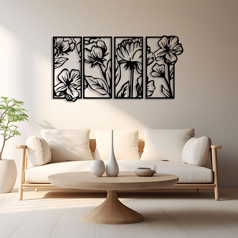 May include: Black metal floral wall art composed of four rectangular panels. Each panel features a different floral design, creating a cohesive botanical theme. The artwork is mounted on a white wall above a light-colored sofa and wooden coffee table.