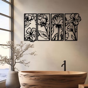 May include: Black metal floral wall art composed of four rectangular panels. Each panel features a different stylized flower design with leaves and stems. The artwork is mounted on a neutral-colored wall, with a wooden bathtub and a window in the background.