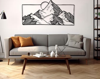 May include: Black metal wall art depicting a mountain range with a sun in the background. The art is hanging on a white wall above a gray couch with orange and gray pillows.
