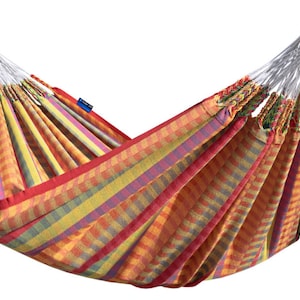 Op de afbeelding: Een kleurrijke gestreepte hangmat met rode, gele, oranje en paarse strepen. De hangmat is gemaakt van geweven stof en heeft witte touwen.