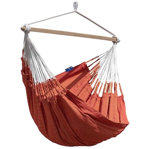 Könnte beinhalten: Ein orangefarbener Hänge-Hängesessel mit einer Holzstange und weißen Halterungen. Die Hängematte besteht aus einem gewebten Stoff und ist zum Entspannen gedacht. Der Stuhl ist an einem einzigen Punkt aufgehängt.