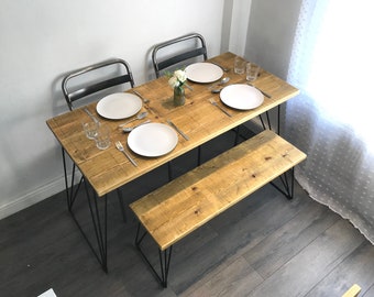May include: A rustic wooden dining table with black metal legs, set for two with white plates, cutlery, and glasses. A matching wooden bench with black metal legs sits on the right side of the table.
