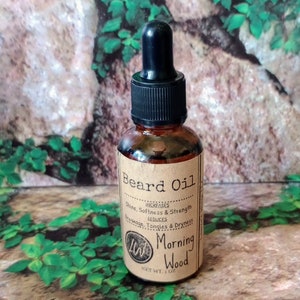 May include: A brown glass bottle with a black dropper top and a brown paper label that reads "Beard Oil" with the text "INCREASES Shine, Softness & Strength REDUCES Breakage, Tangles & Dryness" and "Morning Wood" with the text "NET WT. 1 OZ".