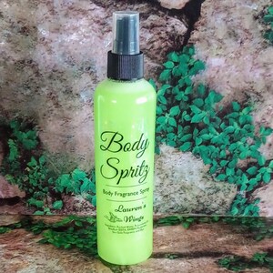 K&ouml;nnte beinhalten: Eine gr&uuml;ne Flasche K&ouml;rperspray mit schwarzem Spr&uuml;hkopf. Das Etikett lautet "Body Spritz Body Fragrance Spray Lauren's Wings".
